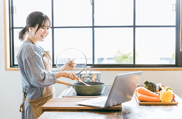 笑顔で調理している女性の画像